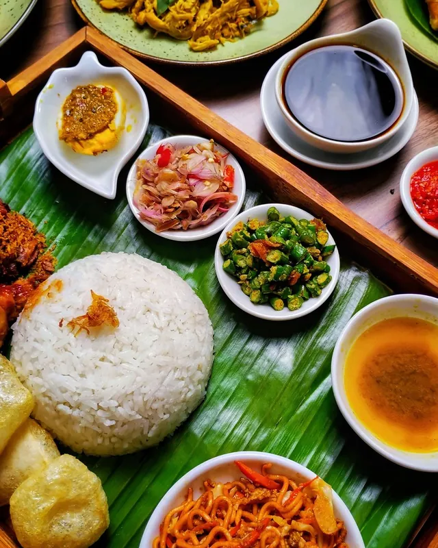 Nasi putih dengan aneka lauk dan sambal di atas daun pisang