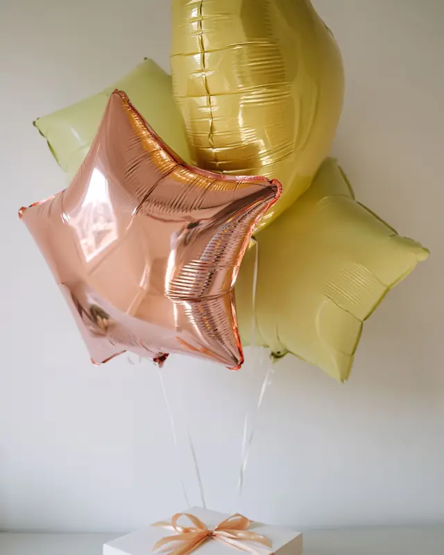 Balon foil bintang dan bulat di atas kotak kado putih