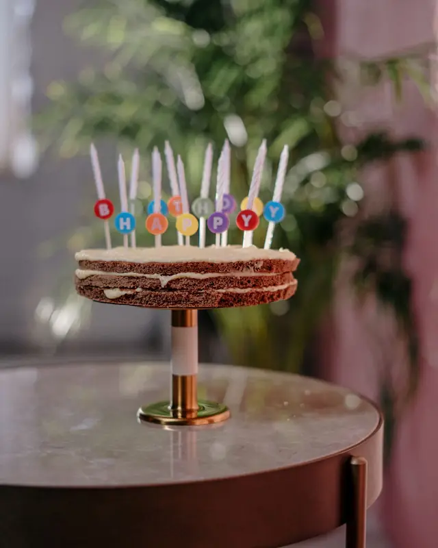 Kue ulang tahun dengan lilin di atas cake stand