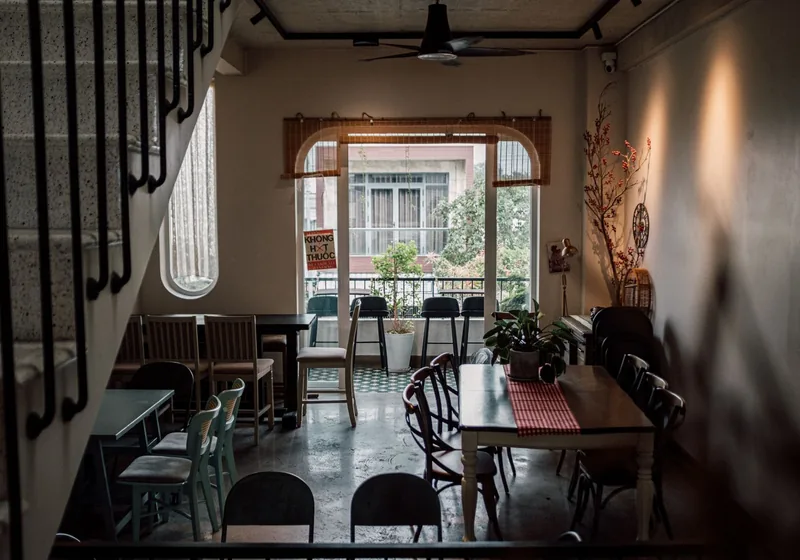 Shophouse café interior with wooden tables, patterned floor tiles and tall windows