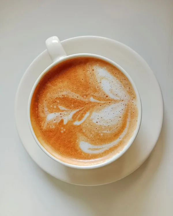 Latte with rosetta art in a white cup, from above