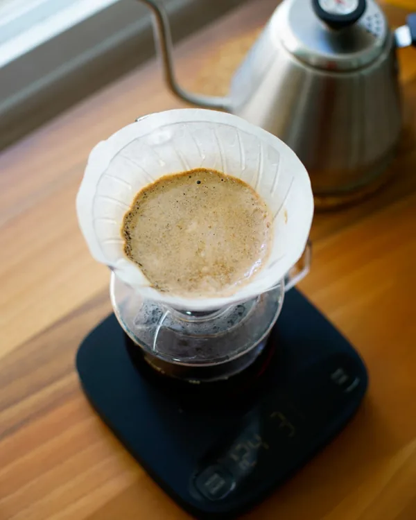 Pour-over coffee dripping through a paper filter on a scale