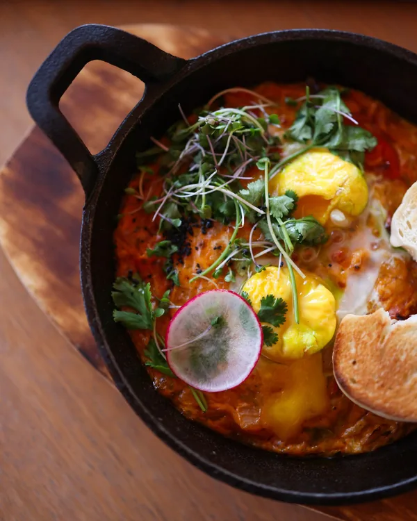 Shakshuka with eggs and herbs in a cast-iron pan