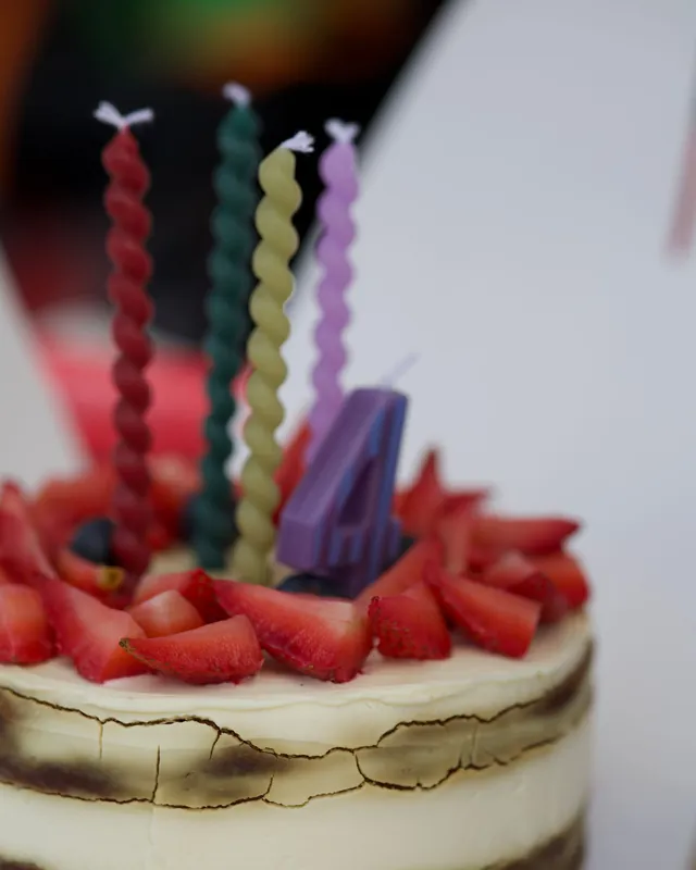 Small strawberry-topped cake with twisted candles in pink, green and purple