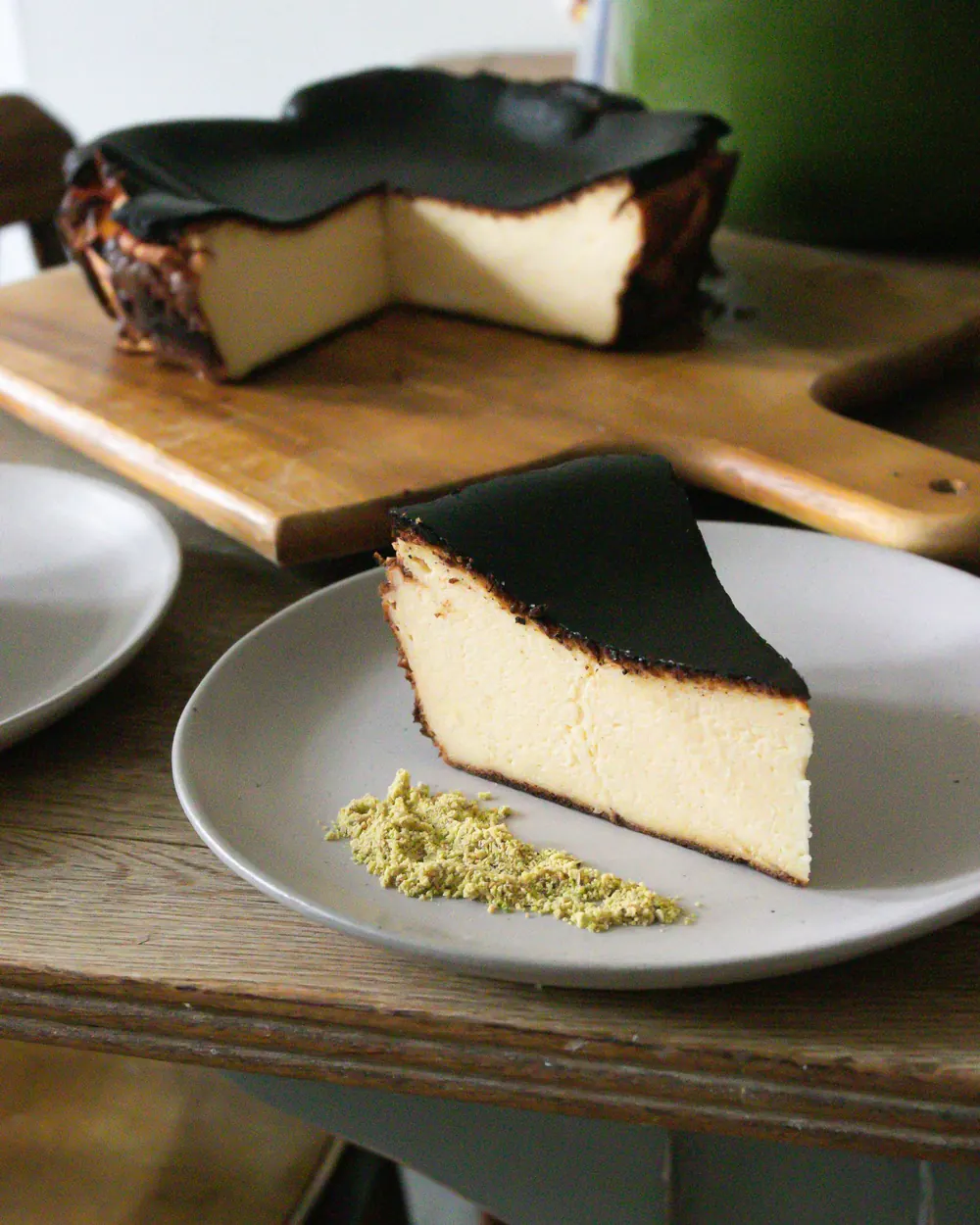 Burnt Basque cheesecake on a wooden board with a slice served on a grey plate