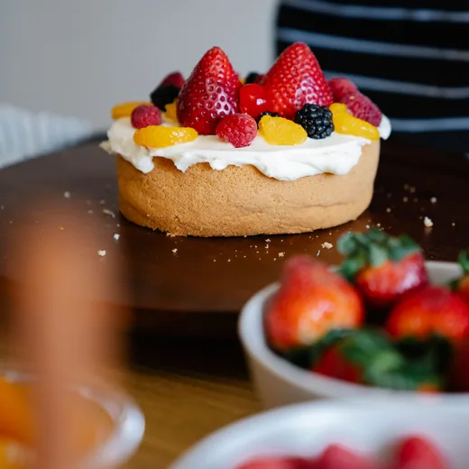 Fresh fruit being arranged on a sponge cake