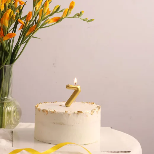 Small white cake with a gold number 7 candle