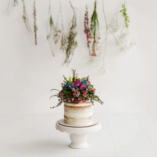 Naked cake topped with fresh flowers on a stand