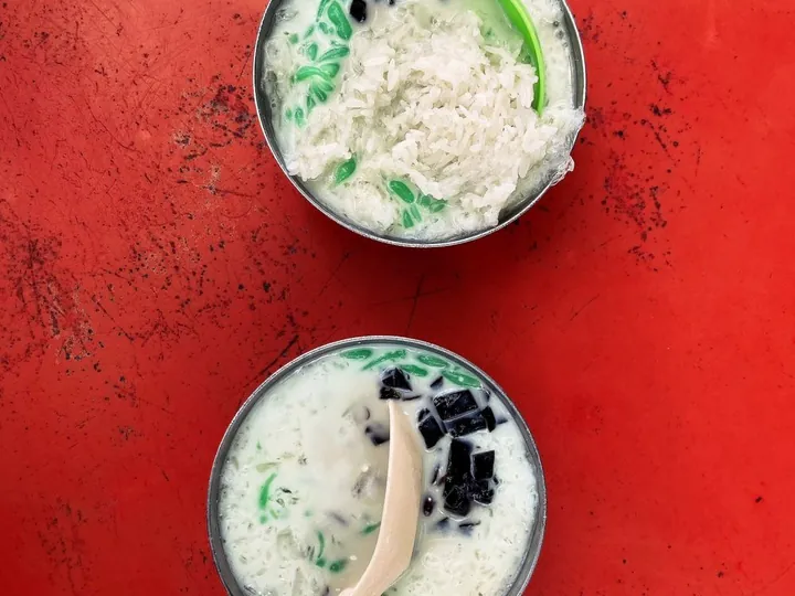 Two bowls of cendol on a red table