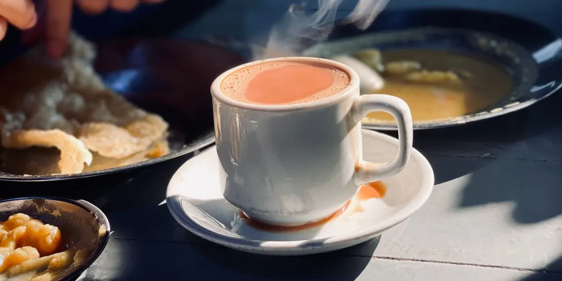 A cup of hot milk tea on a breakfast table in the morning sun