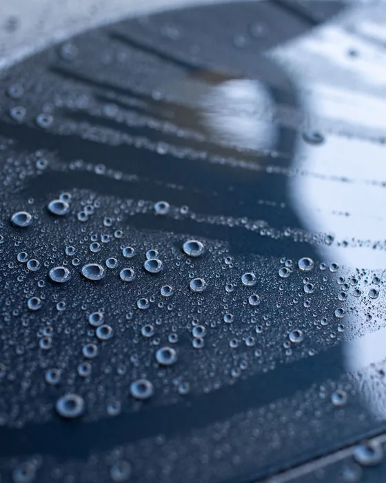 Water droplets beading on a deep blue car panel after coating