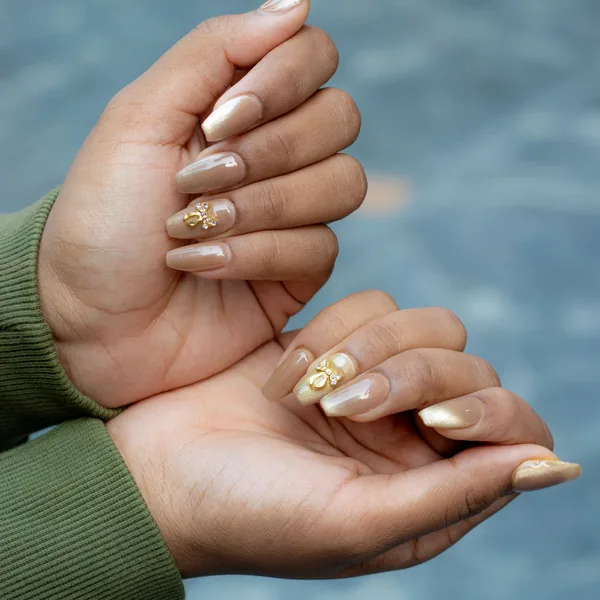 Long nude nails with gold leaf and glitter nail art on every finger