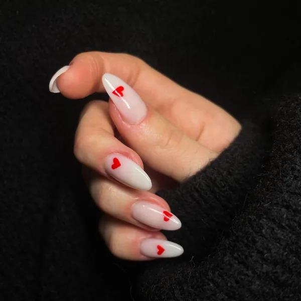 Milky white nails with hand-painted red hearts