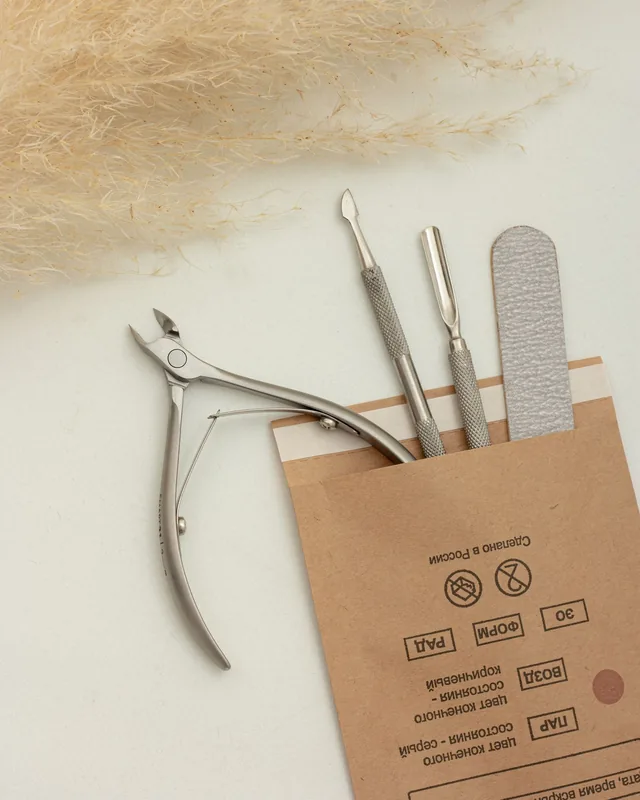 Cuticle nipper, pusher and nail file sliding out of a sealed sterilisation pouch
